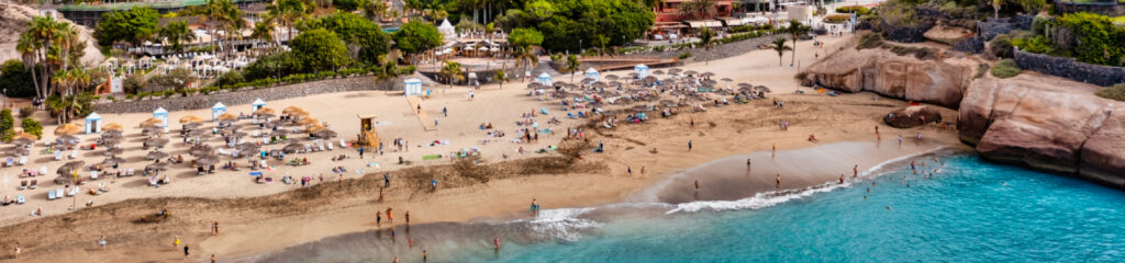 Playa del Duque en Costa Adeje, una playa elegante de arena clara y aguas tranquilas.